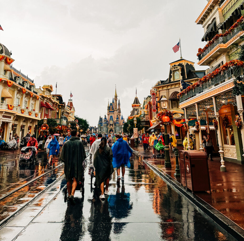 People walking down Disney World's main street while raining