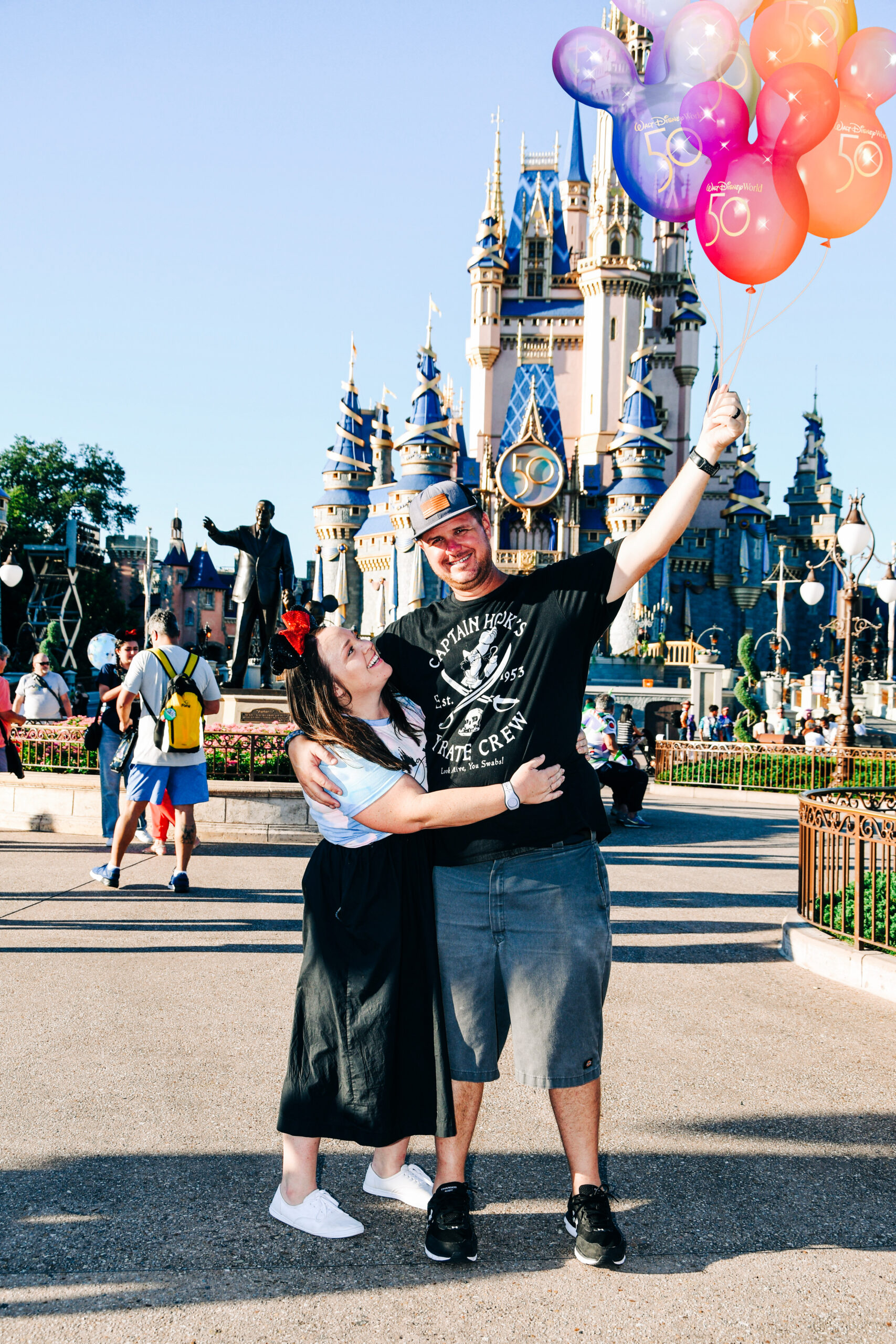 man and woman posing in front of castle with balloons